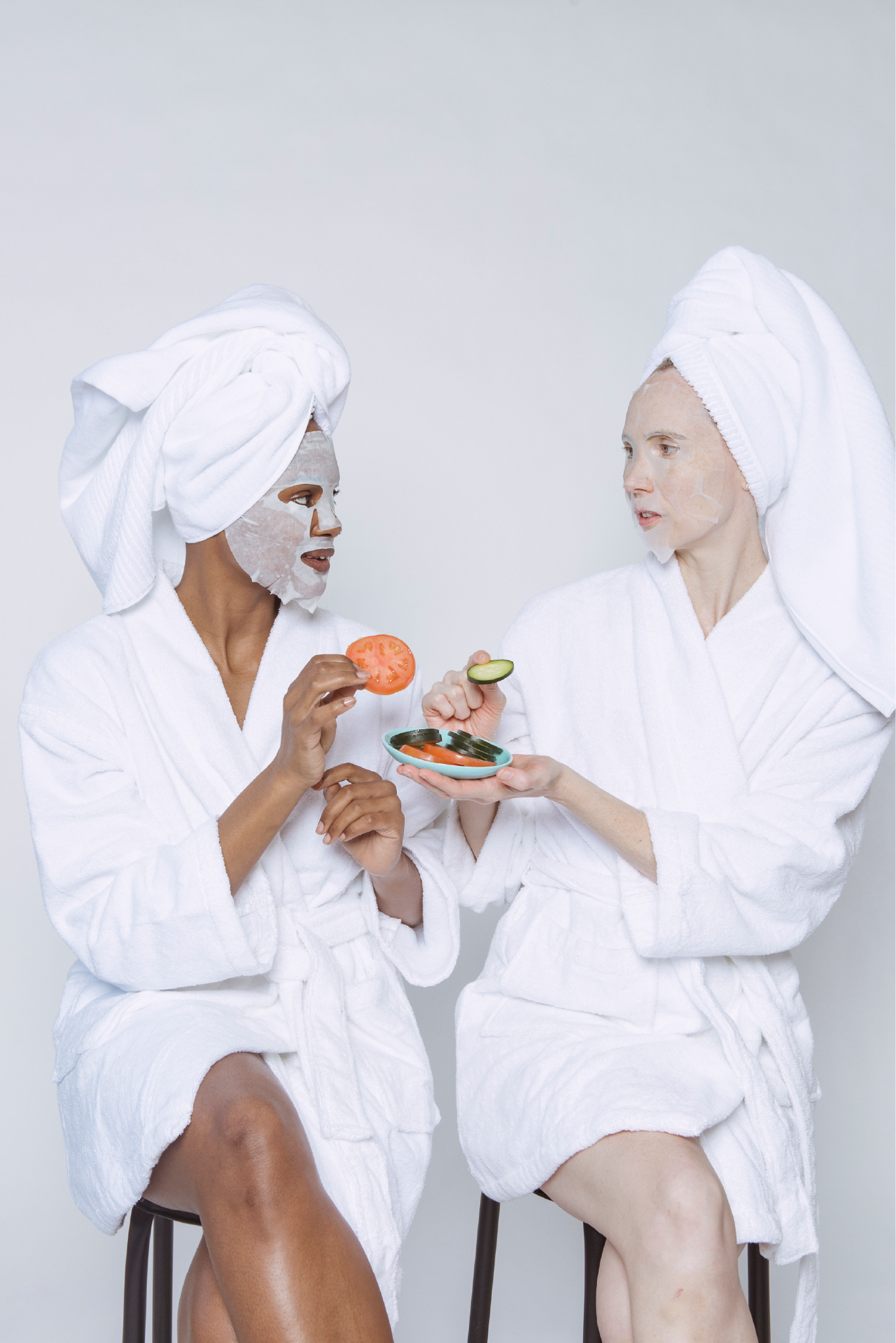 diverse women in sheet masks skin care products wearing bathrobes doing morning skin care routine