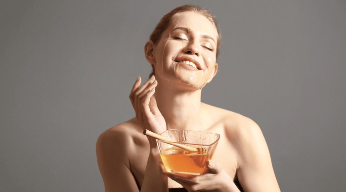 smiling woman applying a homemade honey face mask